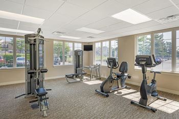 A gym with a variety of equipment including a treadmill, elliptical machines, and a weight machine.